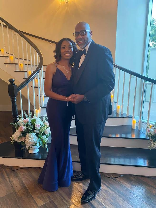 John C. Gilbert in a tuxedo beside a woman in an evening gown on an elegant staircase
